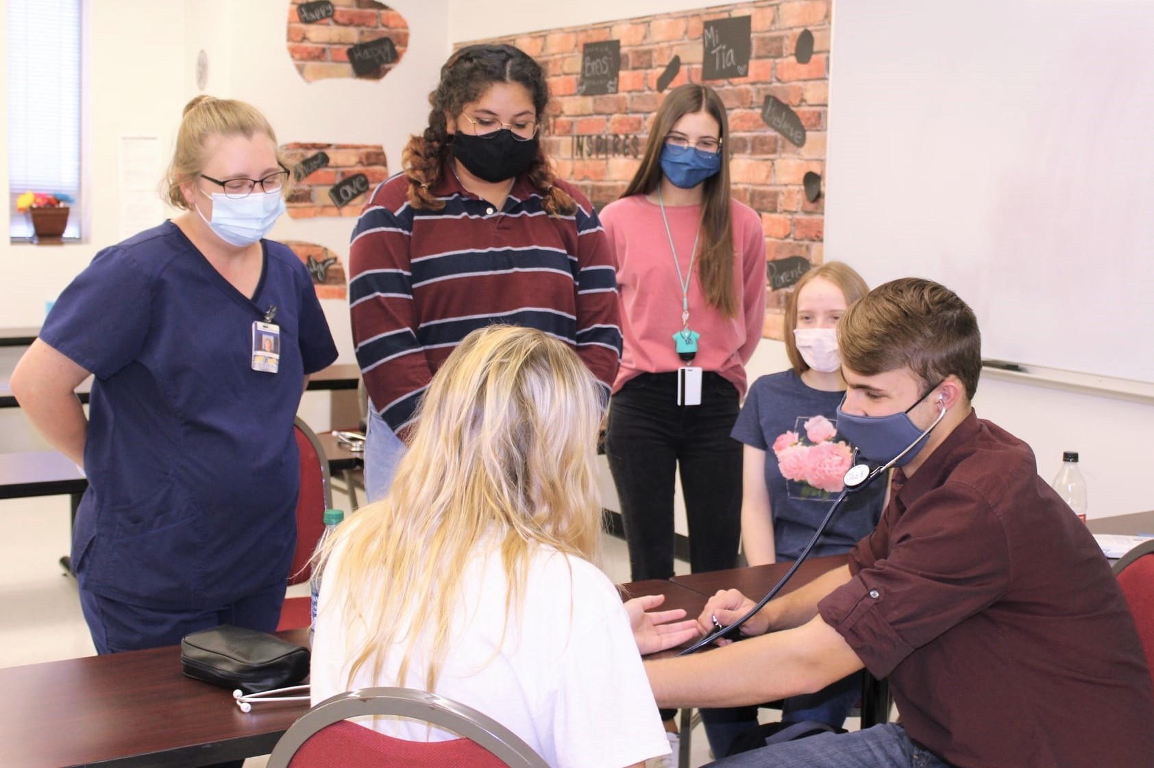 Health Science students watch a student check a patient with a stethoscope