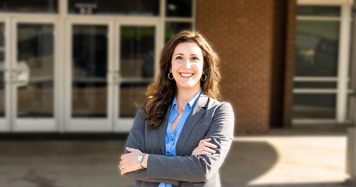 Dr. Logan Maxwell standing outside with arms crossed in front of building entrance