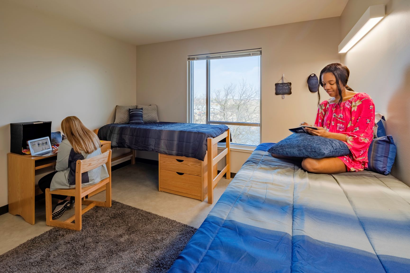 Inside of residence hall room with 2 students studying, from different angle