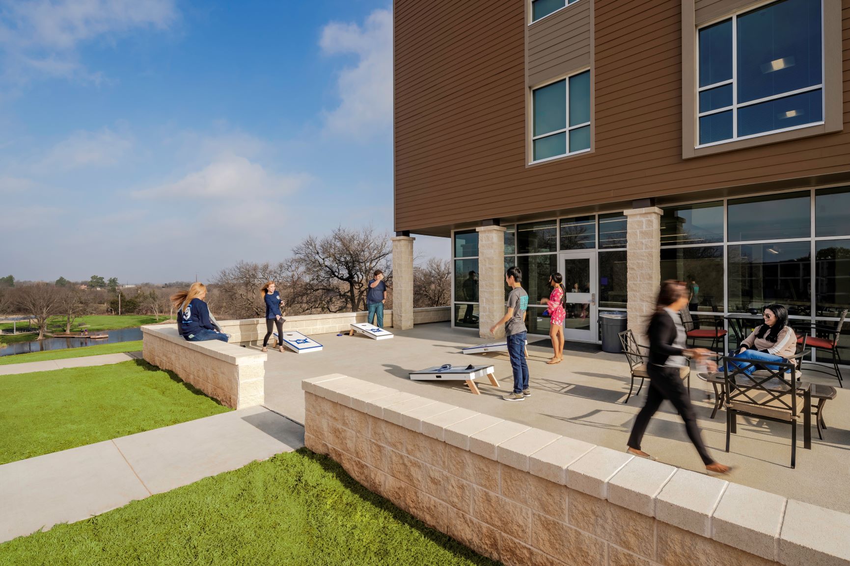 Students hanging out playing cornhole on outdoor patio