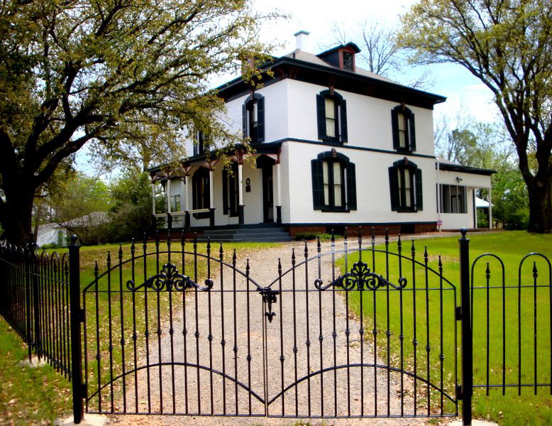 Photograph of white house surrounded by iron fence