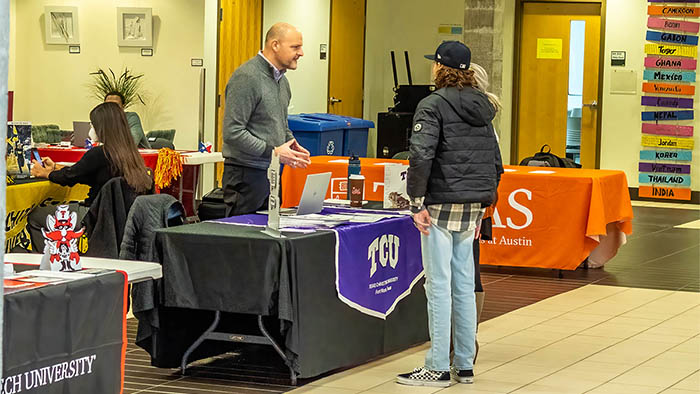 College representative helping a student at a desk during annual college day