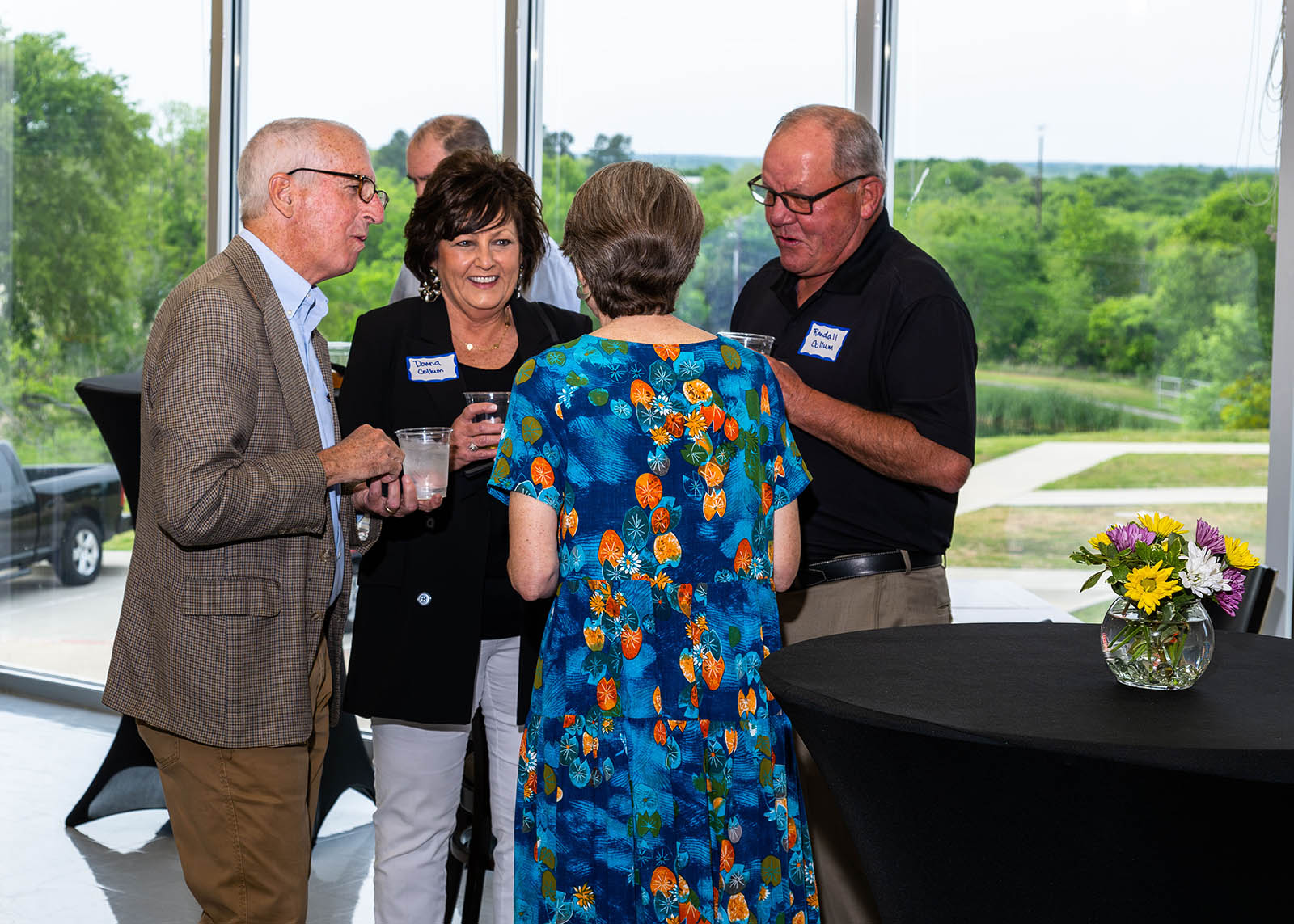 Individual in business casual clothing standing by table socializing