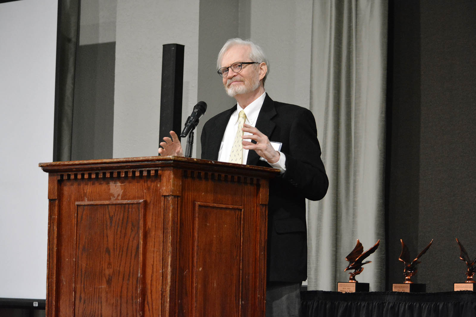 Man speaking while gesticulating with hands at podium