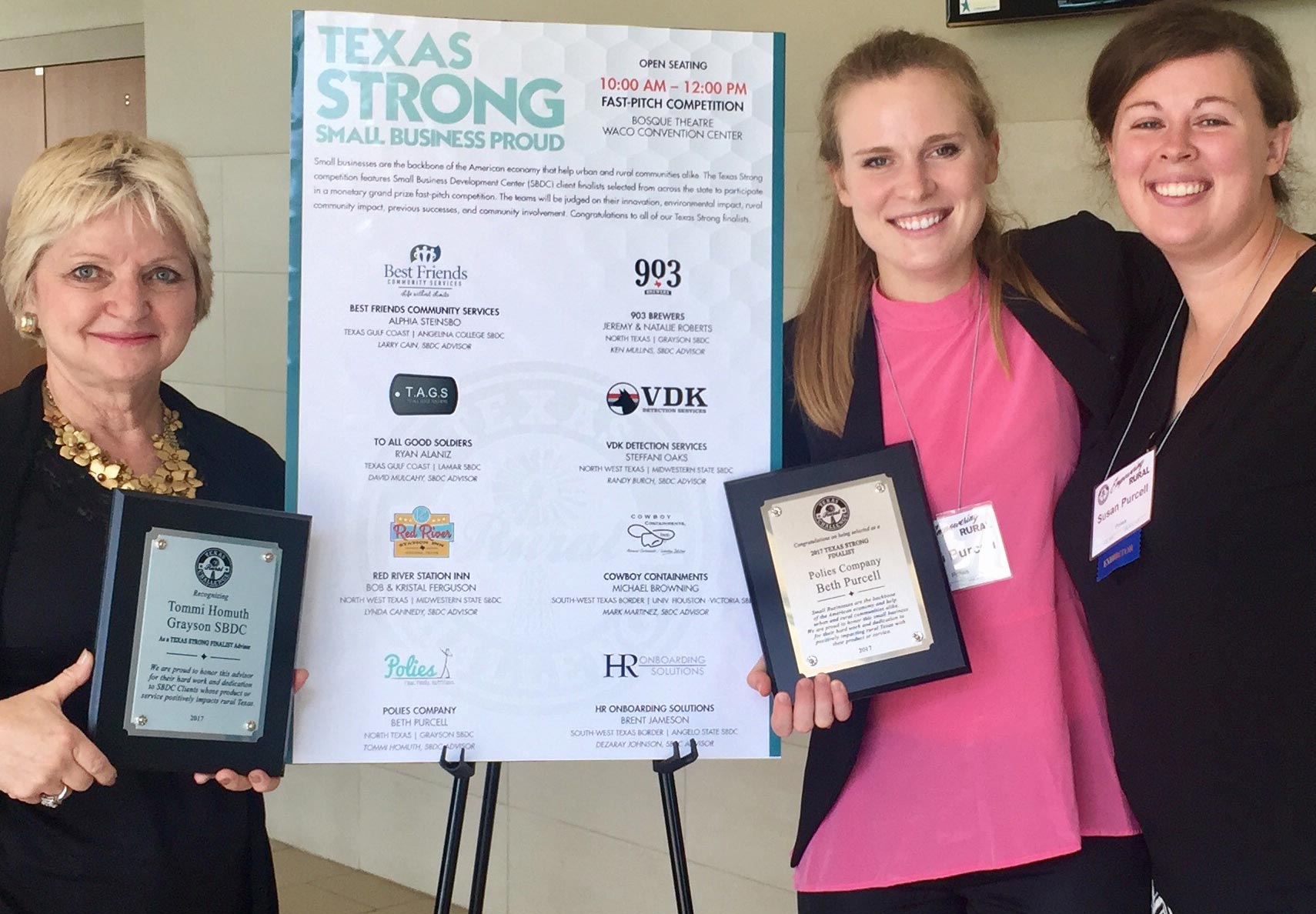 Award winners standing in front of poster holding awards