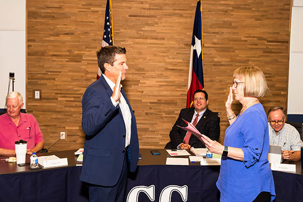 Man in suit coat being sworn in in front of Board of Trustees