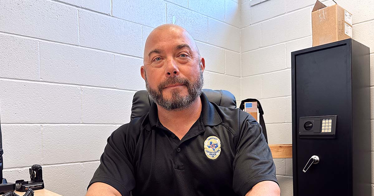 Man in police polo sitting at desk