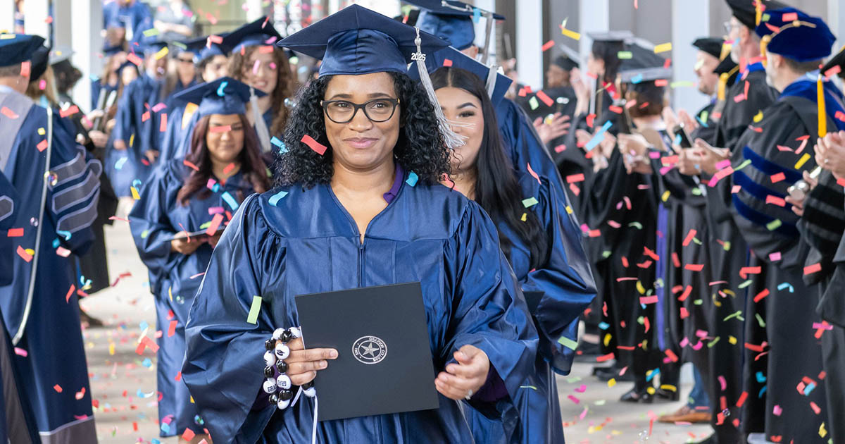 Student in graduation garb holding diploma outside surrounded by confetti