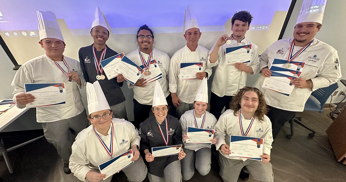Culinary Students in chef attire holding up award certificates