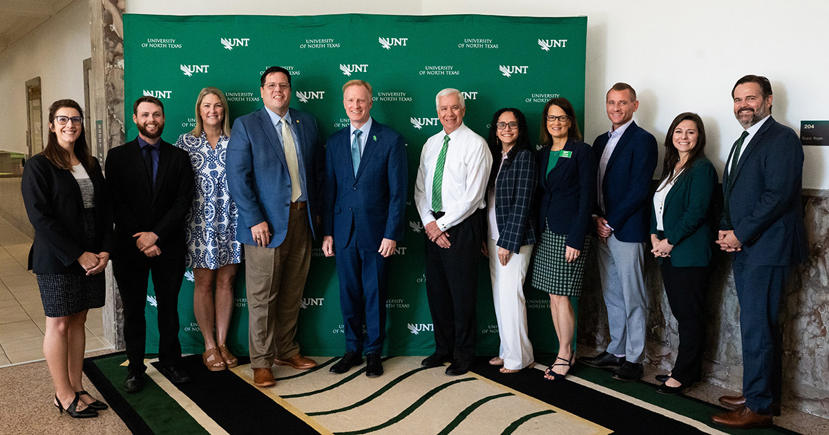 Administration from Grayson College and UNT Standing for photo opportunity in front of UNT green backing
