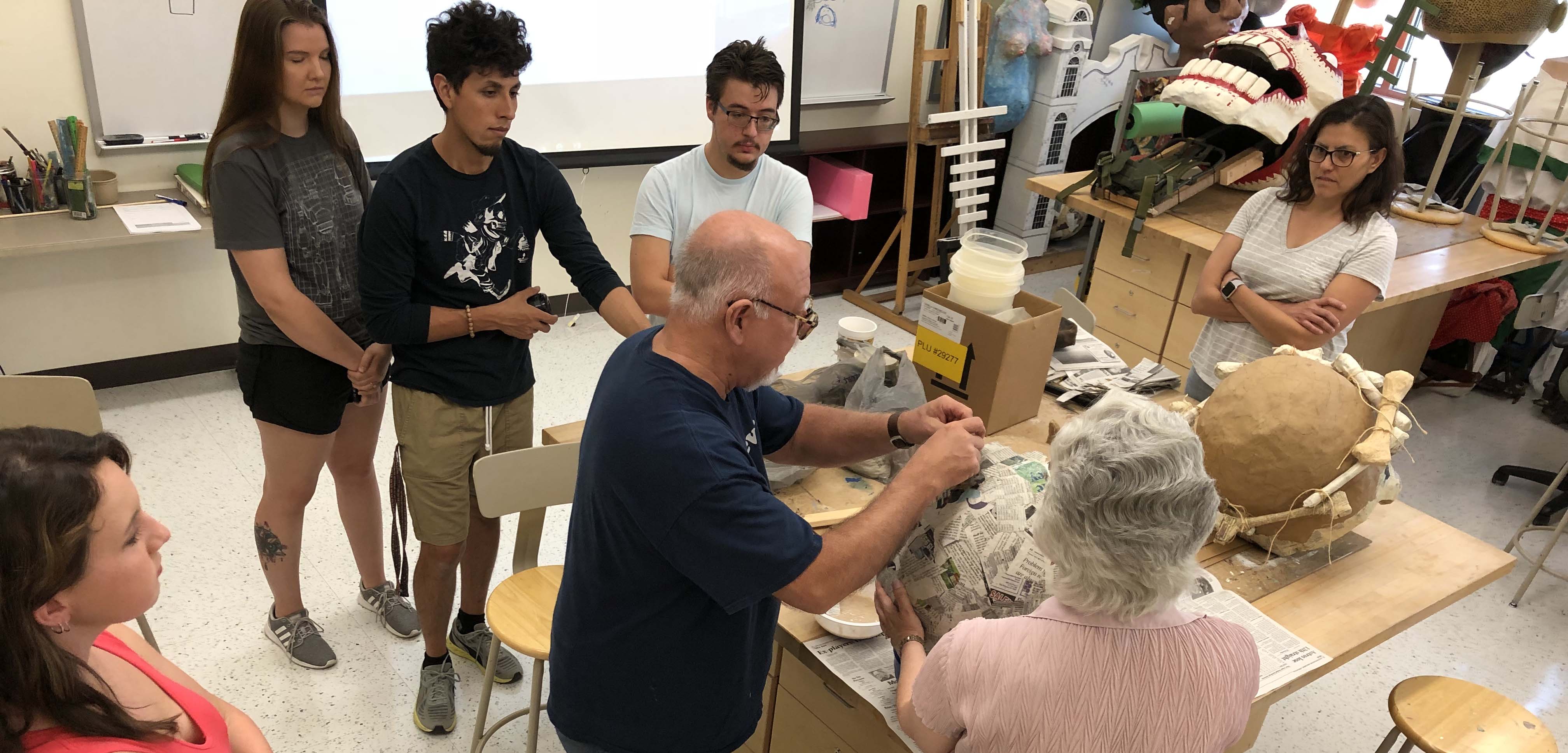 Art students gathered around table working at the puppet workshop